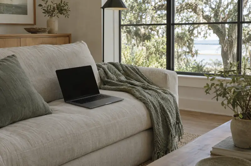 Illustrative photo: a laptop resting on a sofa in a coastal living room
